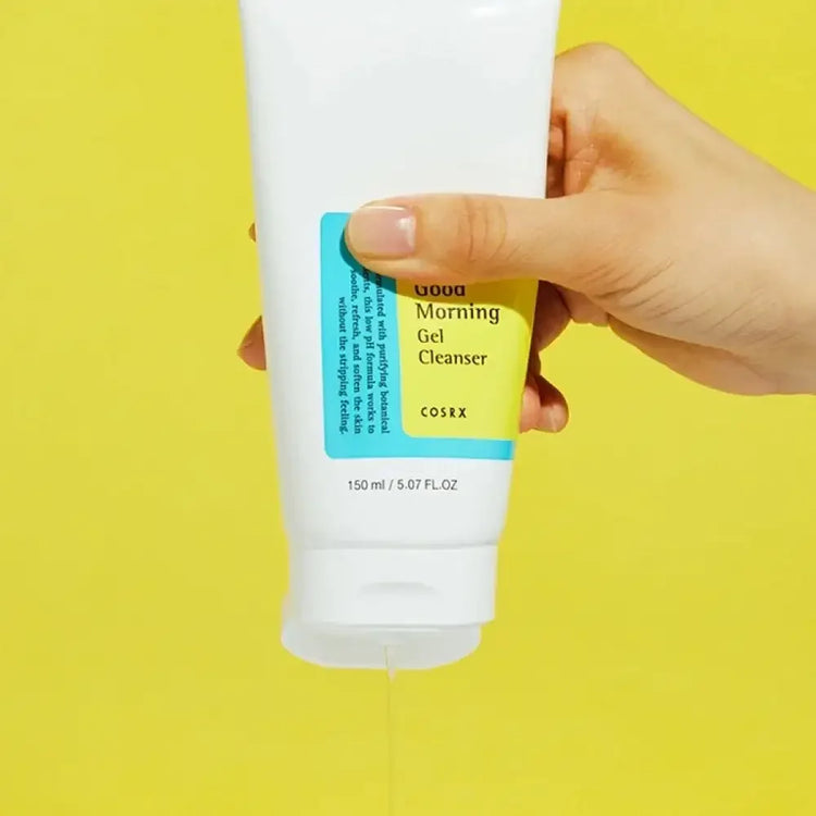 Hand squeezing COSRX Good Morning Gel Cleanser on yellow background, skincare product