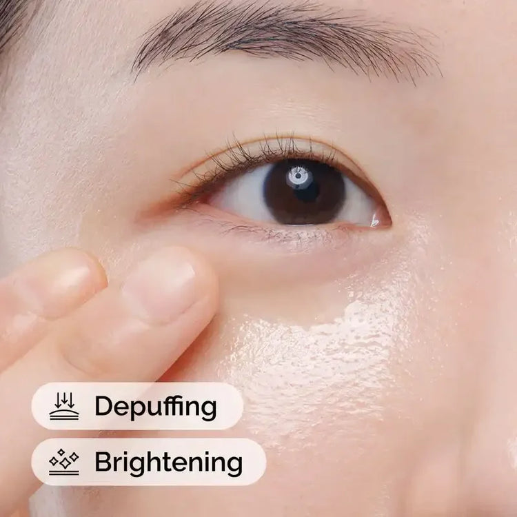 Applying eye cream for depuffing and brightening under eye area, close-up skincare routine