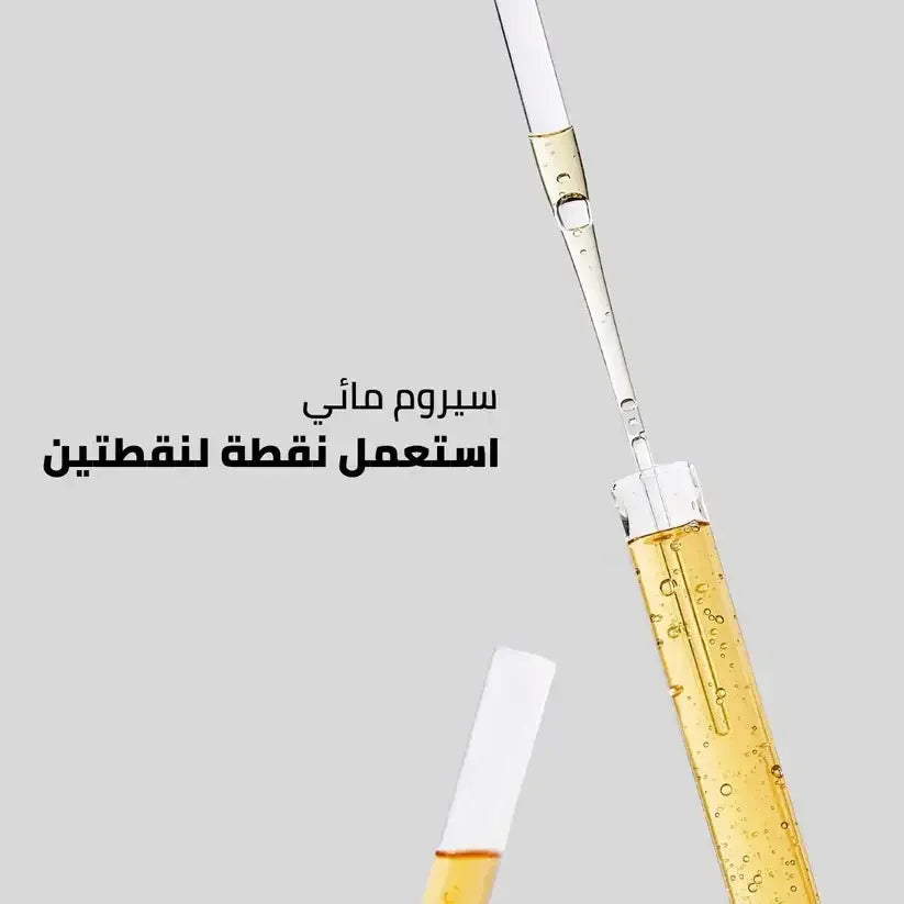 Glass dropper with yellow liquid serum, skincare product on a grey background, Arabic text.