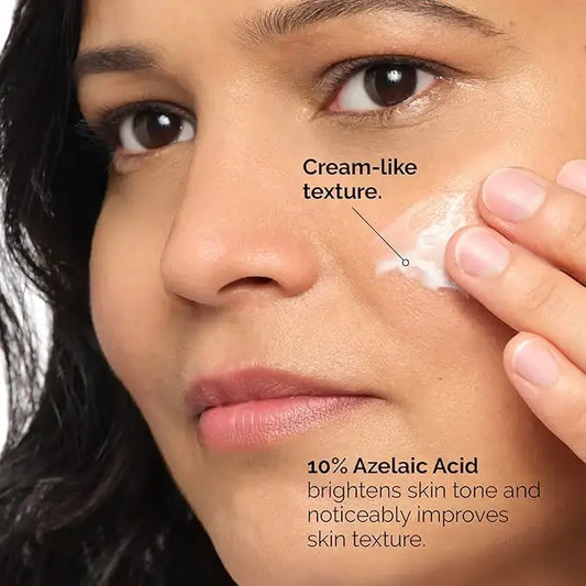 Woman applying 10% azelaic acid cream with cream-like texture to her cheek for skin brightening.