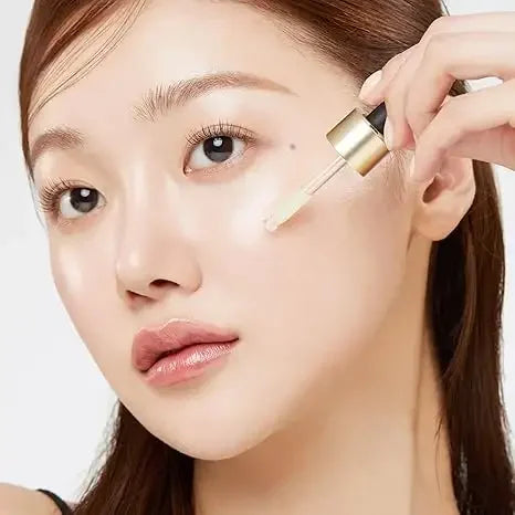 Woman applying Korean skincare serum to face with dropper for glowing skin