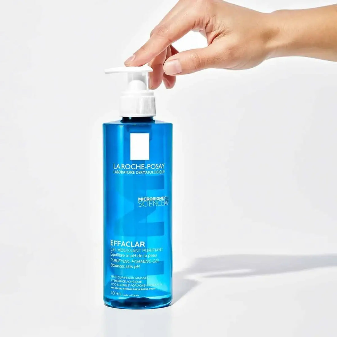 Hand using pump on blue La Roche-Posay Effaclar purifying foaming gel cleanser bottle