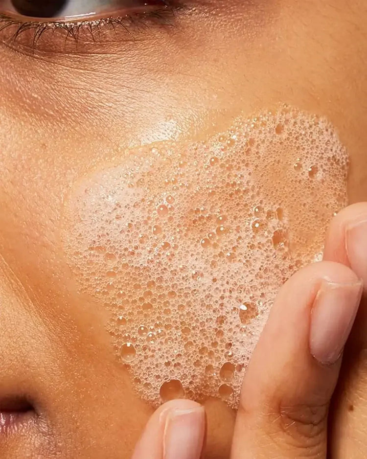 Foaming facial cleanser applied to cheek, skincare routine close-up