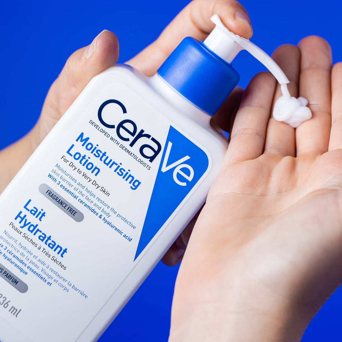 Hand dispensing CeraVe Moisturising Lotion onto palm against blue background