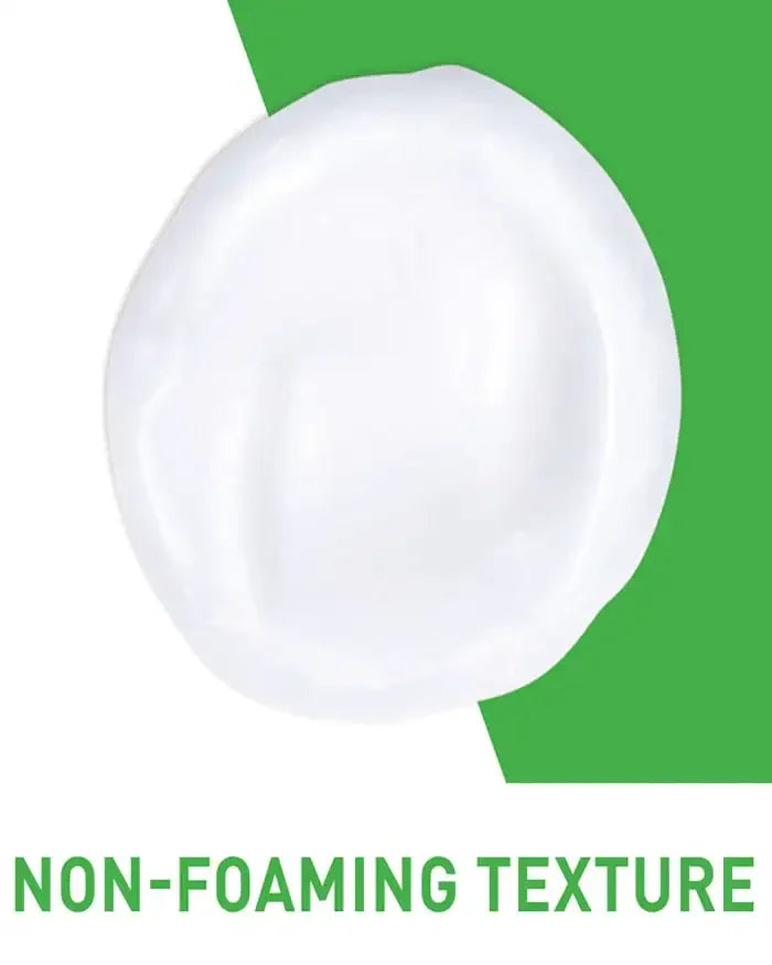 Close-up of a creamy white skincare product with non-foaming texture on a green background