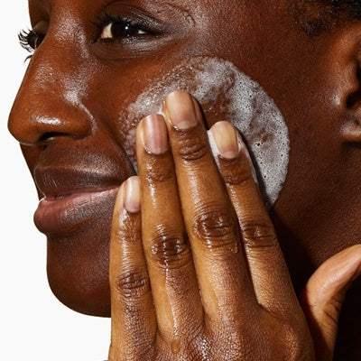Woman cleansing face with foaming facial cleanser for skincare routine