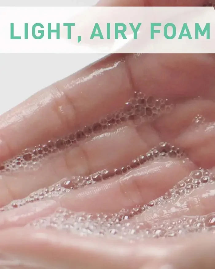 Hand with light, airy foam cleanser bubbles for gentle skincare cleansing