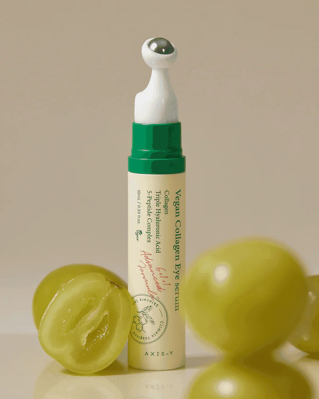 Vegan collagen eye serum with metal applicator, surrounded by fresh green grapes.
