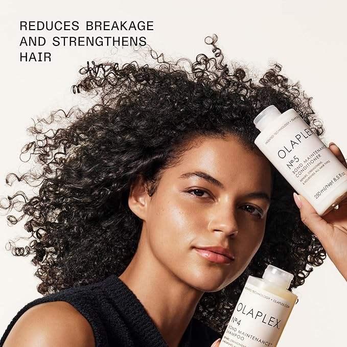 Woman with curly hair holding Olaplex shampoo and conditioner, hair care product focus