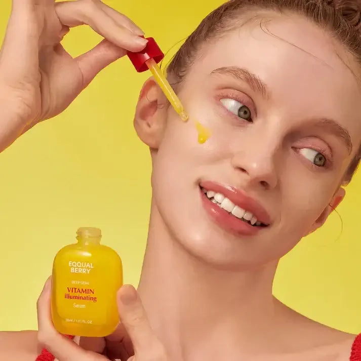 Woman applying Eequal Berry Vitamin Illuminating Serum with dropper on glowing skin